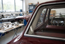 Chrome insert fitted around a maroon classic car's windscreen surround