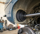 Gaiter fitted over the rear axle tube of a blue classic car on a ramp