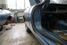 Black sponge seal fitted to a door shut face of a blue classic car, roll of tape in the foreground