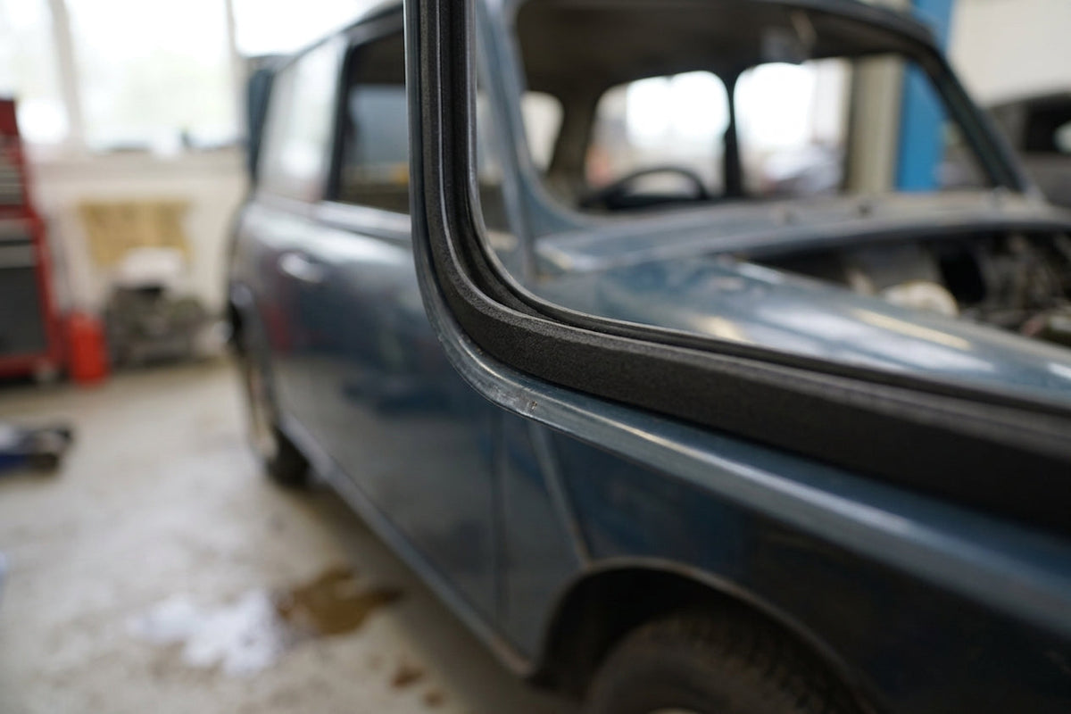 Black sponge strip fitted along the door aperture edge of a blue classic car body