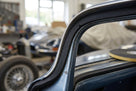 Black sponge strip fitted around a roof pillar of a classic car, adhesive tape roll visible behind