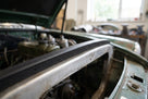 Black sponge trim fitted along a bonnet edge above the engine bay of a green classic car
