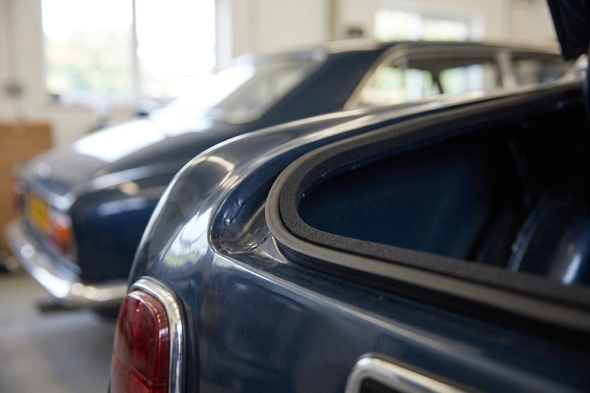 Black sponge trim fitted around a rear window aperture of a dark blue classic coupe