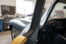 Black sponge strip applied along a door pillar of a dark green classic car, yellow tape below