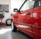 Black door moulding fitted along a red Escort's door edge, workshop with tools