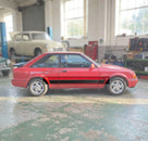 Black door moulding fitted along a red Escort XR3i's waistline, side profile