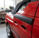 Black door moulding fitted to a red convertible Escort's rear door, close-up