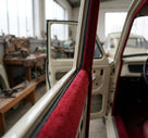 Red wool-pile edge trim fitted around a door frame on a cream classic car