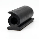 Black hooked sponge seal with round hollow bore and flat mounting foot, paper backing on the base