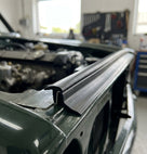 Black edge trim fitted along a bonnet edge on a green classic car
