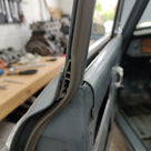 Grey edge trim fitted to a window frame on a blue-grey classic car