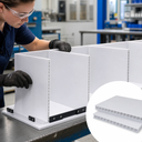 Worker assembling white fluted board dividers on a bench, inset sheets with open flutes showing