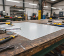 White polyethylene panel on a timber bench with a tape measure across it, snips and screws nearby