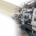 Machine shop with a CNC lathe and parts racking, a pale cream band washing out the left of the frame
