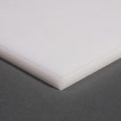 Corner of a natural white HDPE sheet on a grey surface, square-cut edge showing the sheet thickness