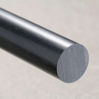 Charcoal-black HDPE rod angled towards the camera, sawn end face lit against a mottled stone-beige backdrop