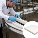 Engineer in a hairnet fitting a curved white side guide to a conveyor bend, inset of a thin white slab