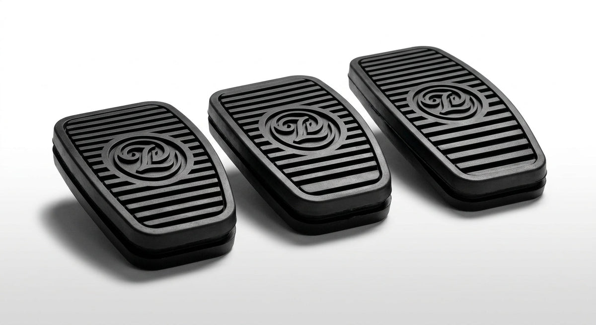 Three black ribbed rubber pedal pads with embossed logo, studio shot