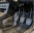 Three black ribbed pedal pads fitted in a Triumph Stag manual footwell