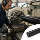 Turner in ear defenders machining a long black nylon bar in a lathe, inset of the plain black rod