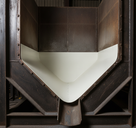 Cream HDPE liner lining the V of a rusted steel hopper, bolted frame and discharge chute below