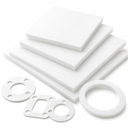 Four white PTFE sheets stacked on white with square and ring gaskets cut from them in front