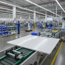 Large milky white HDPE sheet on a roller conveyor in a factory, workers and robot cells beyond