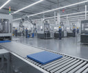 Blue polyethylene panel travelling along a roller conveyor in a factory, staff at CNC machines behind