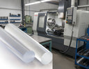 Two clear acrylic rods composited large in front of a CNC machining centre in a workshop