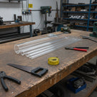 Bundle of clear acrylic tubes on a workshop bench with a hacksaw, tape measure and cutting tools around them.