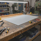 Off-white nylon panel on a timber workbench, milling machine and parts bins behind it