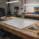 Pale nylon panel laid on a workbench under strip lights, tape measure, pliers and knife nearby