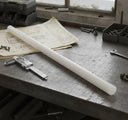 White acetal rod laid across old drawings on a bench with digital callipers and a spanner