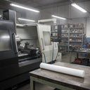 White polypropylene rod on a steel table in front of a black and white CNC lathe