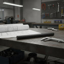 Black HDPE rod on a workshop bench beside folded drawings, callipers and a tool board