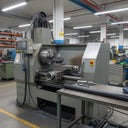 Black HDPE rod on a steel table beside a large industrial lathe on a factory floor