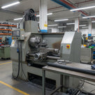 Black HDPE rod on a steel table beside a large industrial lathe on a factory floor