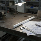 Natural white HDPE rod lit by a bench lamp, with callipers and engineering drawings alongside