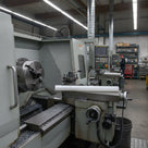 White HDPE rod laid across a machine table in a workshop, lathe chuck and swarf tray in the foreground