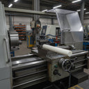 Ivory nylon 6.6 rod resting on a lathe bed in a machine shop with swarf on the ways