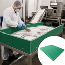 Fish packed in ice inside a green-sided steel table, worker in whites raking with a scoop