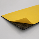 Thin self-adhesive rubber sheet on a white surface, yellow liner lifted to show the tacky underside