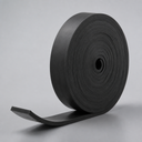 Coil of thick black rubber strip standing on end, square-cut tail lying flat on a pale grey surface