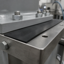 Black rubber strip set as packing between two bolted steel frame sections on machinery