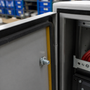 Grey control cabinet doors with black sponge rubber sealing strip and yellow liner, storage bins behind