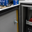 Grey control cabinet doors with black sponge rubber sealing strip and yellow liner, storage bins behind