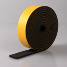 Deep roll of black sponge rubber strip on edge, broad yellow adhesive face and a chunky flat tail