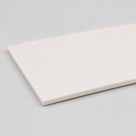 Off-white silicone sheet lying flat on grey, one long square-cut edge facing the camera