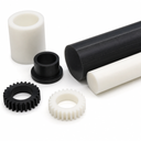 Black and white acetal rod with machined gears, bushes and a sleeve grouped on a white background