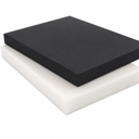 Thick black acetal slab resting on a white one against a white background, sawn edges facing forward
